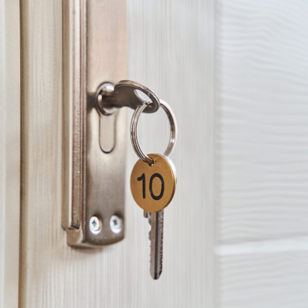 A key with a key fob in the keyhole of the door. Buy a new home concept. Real estate market. A key with a key fob in the keyhole of the door. Buy a new home concept. Real estate market. High quality photo