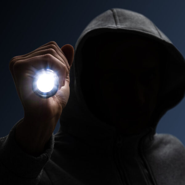 Hooded burglar. Silhouette of thief and flashlight Hooded burglar. Silhouette of thief and flashlight.