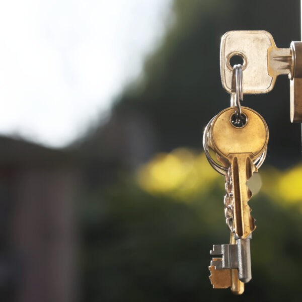 House keys in lock of a door viewed outside horizontal_rt House keys in lock of a door viewed outside with soft glow background from natural lighting. Room for text. This image is also available in vertical orientation